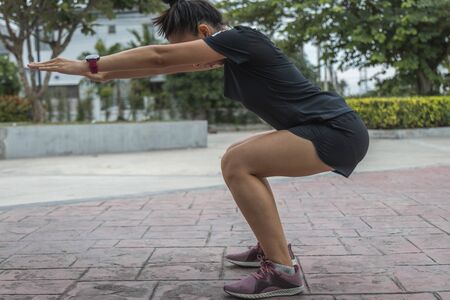 The Young female workout before fitness training session at the park. Healthy young woman warming up outdoors.の写真素材
