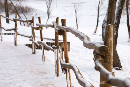 Wooden fence, sidewalk and couple of trees with fresh snowの写真素材