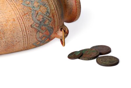Ancient jug with a couple of coins over white backgroundの写真素材