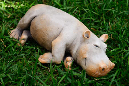 Small clay hippopotamus laying over green grassの写真素材