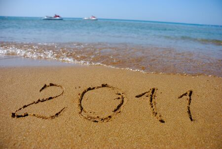 Numbers 2011 wrote on the sunny sand beach of Mediterranean Sea with 2 waverunners on the horizon