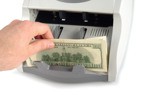 Male hand putting the money into the bill counter isolated over white with clipping pathの写真素材