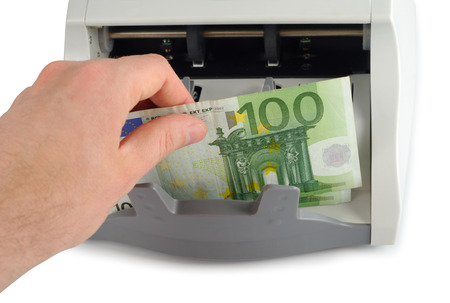 Male hand putting the money into the bill counter isolated over white with clipping pathの写真素材