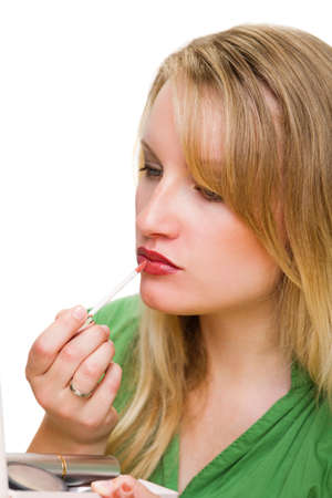 Close-up of a beautiful young woman applying red lip glossの写真素材