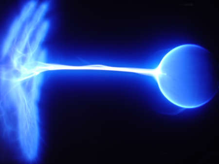Blue static electricity arc traveling from a plasma ball to an open hand. Horizontal shot.の写真素材