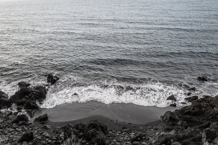 Black sand beach aerial view. Grey and black volcanic rocks and ocean wavesの写真素材