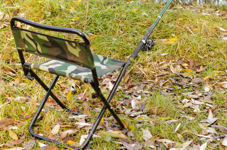 Fishing tackle ashore among fallen down leaves autumn a fishing chairの写真素材