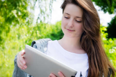 attractive casual young girl working on a touch screen tablet in the parkの写真素材