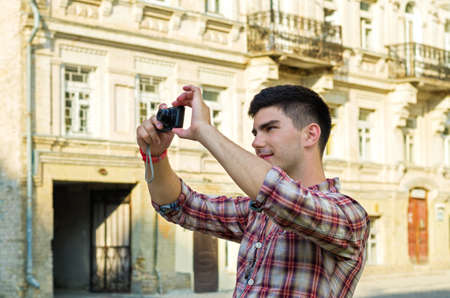 Young man standing taking photographs with a compact camera outside an old historical buildingの写真素材