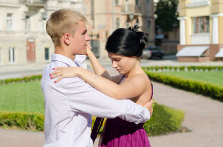 Stylish young couple holding each other and ballroom dancing in a town square in the sunshineの写真素材