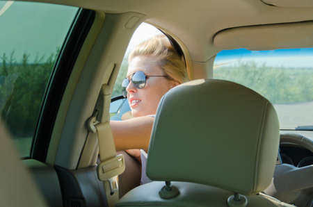 Attractive female driver looking through window of her car