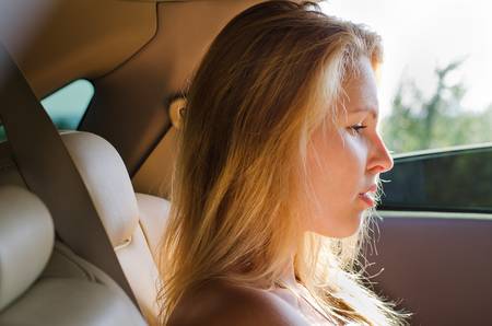 Profile of an attractve dejected blonde woman sitting in a carの写真素材