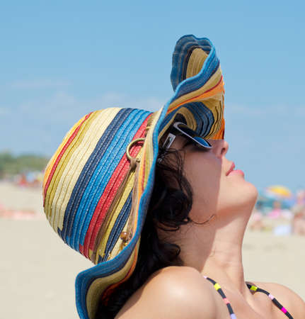Woman with sunglasses and colorful hat enjoying on beachの写真素材