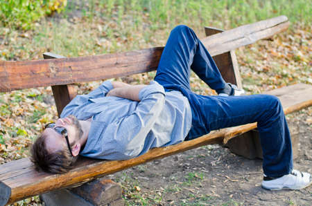 Man with sunglasses relaxing in park on wooden benchの写真素材
