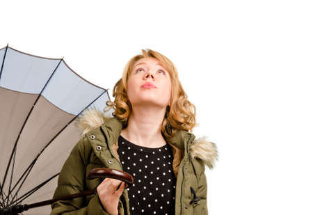 Attractive blonde woman holding an umbrella standing with her head tilted right back looking at the sky as she contemplates the weather isolated on whiteの写真素材