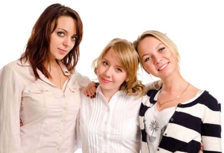 Three happy attractive young female friends socialising together standing in a row smiling at the camera isolated on whiteの写真素材