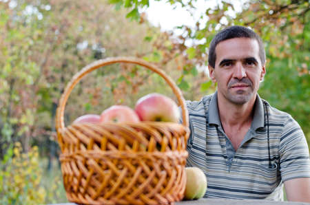 Portrait of smiling man with a fruit basket outdoorの写真素材