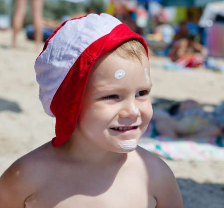 Happy little boy on summer vacation smiling in anticipation of playing in the sea as he stands on...