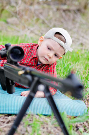 Portrait of boy on the grass playing with a toy shotgun outdoorの写真素材