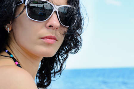 Portrait of a brunette on the beach wearing sunglassesの写真素材