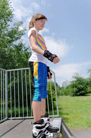 Young girl poised at the top of a skating ramp standing in her skate 