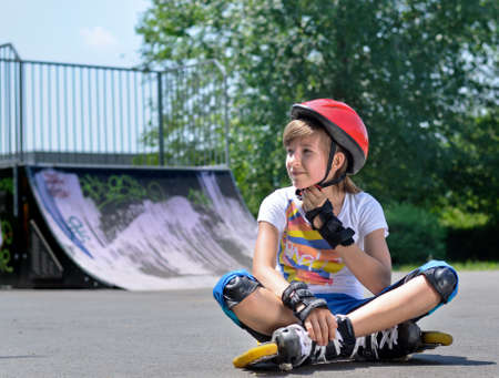 Pretty teenage girl in roller skating gear with a safety helmet, rollerskates and hand and wrist...