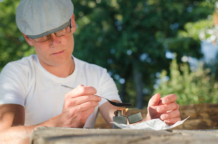 Man disolving heroin with a lighter in the outdoorsの写真素材