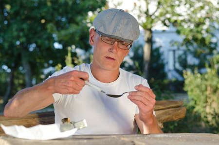 Portrait of an addicted man filling a syringe with soluble heated heroin outdoorsの写真素材