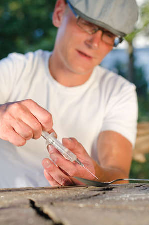 Vertical portrait of a Caucasian man filling a syringe with soluble addictive drugの写真素材