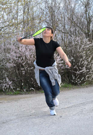 Attractive woman playing badminton running across and looking up into the air watching the...