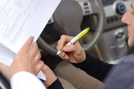 Woman driver signing paperwork for the purchase or insurance on a new vehicle