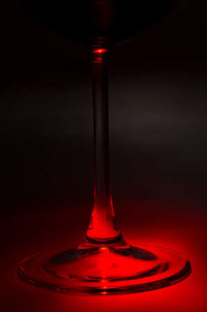 Close-up of the stem and foot of a wine glass in a red lightの写真素材