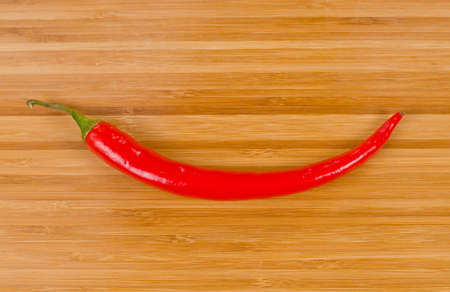 Vegetable smile formed from a whole fresh red hot chilli pepper for wood backgroundの写真素材