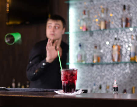 Barman serving a customer in a nightclub looking round attentively as someone places an order for a drinkの写真素材