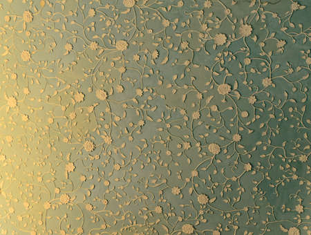 Decorative plasterwork on a wall with an intricate pattern of trailing flowers and leaves in white on a blue backgroundの写真素材