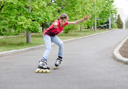 Attractive teenage girl roller skating on roller blades on a tarred rural road rounding a bend at speed with her arms flyingの写真素材