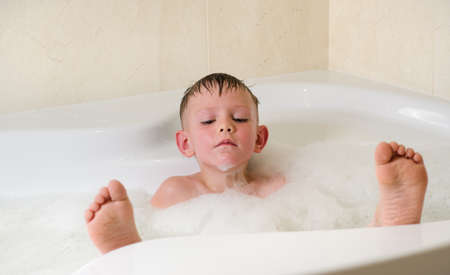 Little boy with eyes closed having a relaxing bubble bathの写真素材