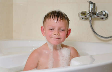 Young boy with a smirk on his face bathing in the tub