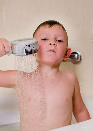 Boy holding shower over his head bathing in the bathroom