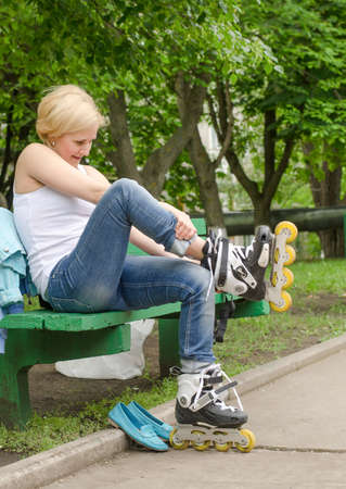 Young girl sitting on a bench removing her rollerbladesの写真素材