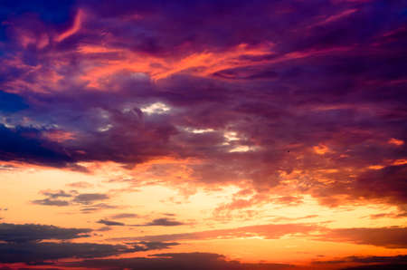 Celestial background of a dramatic beautiful fiery orange and purple sunset lighting up the cloudsの写真素材