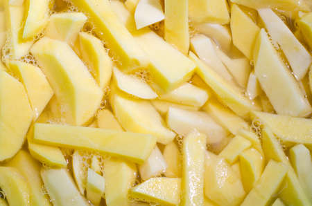 close up view of freshly cut homemade potato chips frying in oilの写真素材