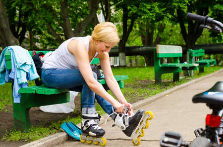 Young girl sitting on a bench removing her rollerskates