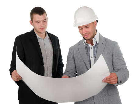 Architect discussing a blueprint with his partner as they stand close together holding the plan unrolled between them gesturing at a specific detail, on whiteの写真素材
