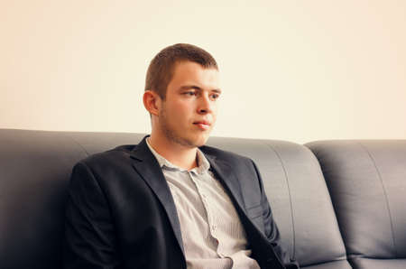 Close up Sitting Gorgeous Young Man in Black Corporate Coat Looking at Camera Whileの写真素材