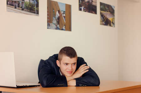 Young Businessman Resting Head on Desk and Looking Optimisticの写真素材