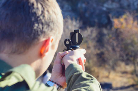 Rear View of a Boy Scout Navigating in the Wilderness While Taking a Reading on a Mountain with his Magnetic Compass Deviceの写真素材