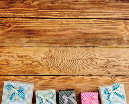 Row of Wrapped Gift Boxes Arranged at Top of Image with Ample Copy Space on Wooden Background as seen from Aboveの写真素材