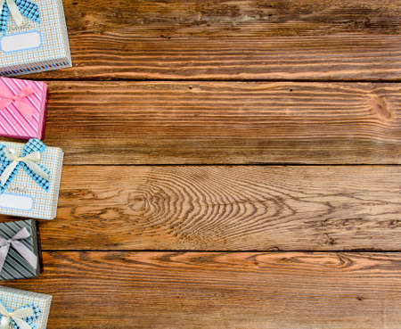 Row of Wrapped Gift Boxes Arranged Vertically Along Side of Image with Copy Space on Wooden Background from Aboveの写真素材