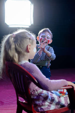 Funny Cute Boy with Mime Makeup Laughing at the Face of his Girl Play Partner While Sitting at the Backstage.の写真素材